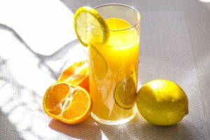 Verre de jus d'orange avec une tranche sur le bord et un citron sur le côté