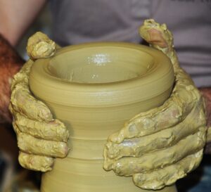 Pot d'argile jaune tenu entre 2 mains