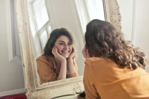 femme qui sourit face à son miroir : Symbole d'une mentalité optimiste grâce à la pensée positive !