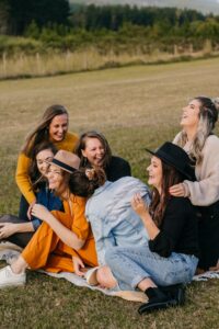 Groupe de femmes qui discute et rigolent ensemble assises dans l'herbe