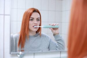 femme devant miroir qui brosse ses dents